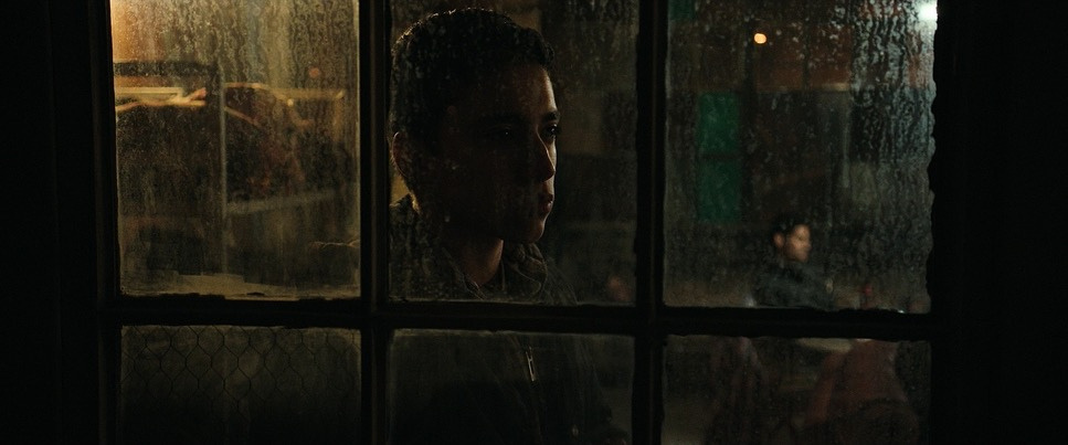 Rain-streaked amber windows and a face in shadow