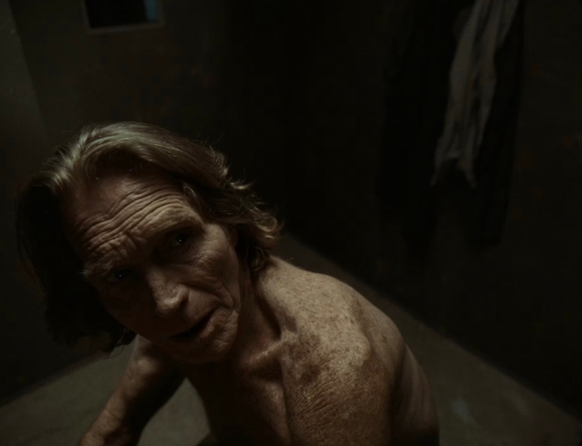 Film still of Joseph Lloyd Lopez crouched in a dark room